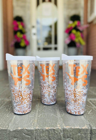 Clear Texas tumbler with burnt orange logo, white lid, and floating glitter