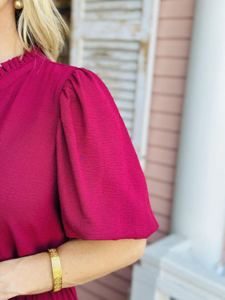Woman wearing Annalise Berry Jumpsuit with ruffle collar and waist tie

Front view of Annalise Berry Jumpsuit with V-neckline and balloon sleeves

Textured berry jumpsuit with removable waist tie and wide-leg silhouette