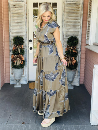 Indie Dress in olive with white bird print and tiered maxi silhouette

Cap sleeve maxi dress with collar, V-neckline, and self-tie waist

Olive green tiered maxi dress featuring bold white bird pattern

Indie Dress with collared V-neck, tiered skirt, and waist tie

Sleeveless maxi dress with cap sleeves and statement bird print