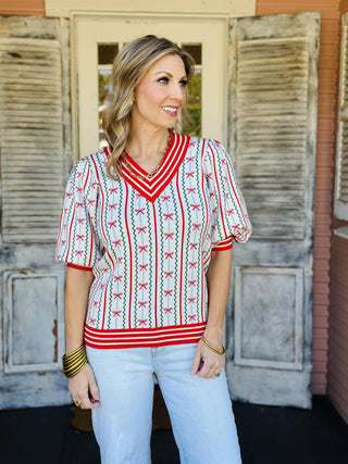 Ivory Christmas Bow Sweater with red and green holiday pattern

Festive ivory knit sweater with red bows and stripes

Holiday bow print sweater with puff sleeves and striped trim

Ivory and red Christmas sweater with green zigzag detailing

Vintage style holiday sweater with red bow pattern