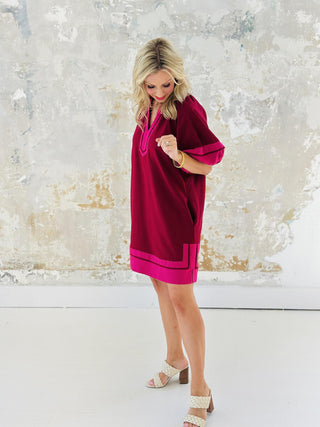 Woman wearing Amanda Dress in burgundy with pink contrast accents

Short lantern sleeve Amanda mini dress with split collar band

Amanda Dress in woven mid-weight fabric with slit hem

Stylish burgundy pullover mini dress with contrast detailing