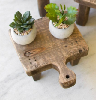 “Wooden cutting board risers styled with small succulents”