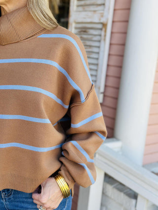 Woman wearing camel and blue striped turtleneck sweater

Cozy striped high-low turtleneck sweater in camel

Bonnie Sweater with blue horizontal stripes and relaxed fit

Brown and blue stripe fall sweater with ribbed hem

Drop shoulder camel stripe turtleneck sweater
