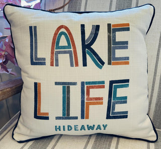 Lake Life Hideaway decorative throw pillow with colorful modern typography and navy piping for lake house décor.