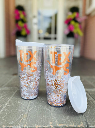 Clear Texas tumbler with burnt orange logo, white lid, and floating glitter