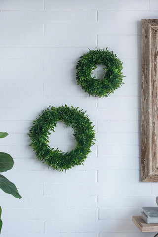 artificial boxwood greenery wreath hanging on white wall decor