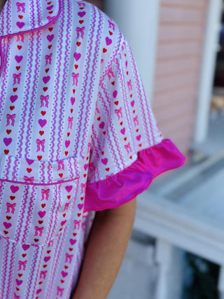 Oh So Lovely Pajama Pants Set with pink heart print, ruffled sleeves, and ruffle hem pants

Pink button-down pajama set with heart pattern and ruffle details

Women’s ruffled pajama pants set with drawstring waist and button-front top

Romantic heart print pajama set with ruffled sleeves and pant cuffs