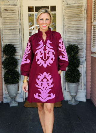 Isabelle Dress in deep burgundy with pink baroque floral appliqué, ruffled neckline, front button detail, and 3/4 sleeves.
