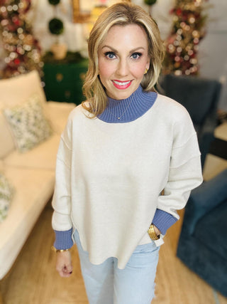Neutral knit sweater with blue ribbed turtleneck and cuffs

Bethany Sweater Top with contrast blue neckline and sleeves

Long sleeve beige pullover sweater with ribbed details