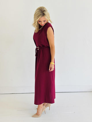 Woman wearing Miley Burgundy Dress, sleeveless burgundy midi dress with gold belt accent

Miley Burgundy Dress with muscle shoulder design and slit hem

Burgundy midi dress with gold embellished belt and back keyhole closure

Elegant sleeveless burgundy dress styled with strappy heels