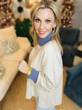Neutral knit sweater with blue ribbed turtleneck and cuffs

Bethany Sweater Top with contrast blue neckline and sleeves

Long sleeve beige pullover sweater with ribbed details