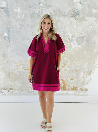 Woman wearing Amanda Dress in burgundy with pink contrast accents

Short lantern sleeve Amanda mini dress with split collar band

Amanda Dress in woven mid-weight fabric with slit hem

Stylish burgundy pullover mini dress with contrast detailing