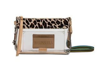 Consuela Mona Clear Midtown Crossbody featuring a transparent body, leopard print trim, natural leather accents, and a colorful woven adjustable crossbody strap.