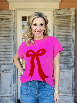 Bright pink knit Lilah Top with red bow detail on front, short sleeves

Women’s pink sweater top with textured red bow design, casual chic style

Close-up of pink knit Lilah Top fabric with raised red bow applique

Short sleeve pink knit top with bold red bow graphic, women’s fashion

Lilah Top pink sweater styled with jeans for everyday wear