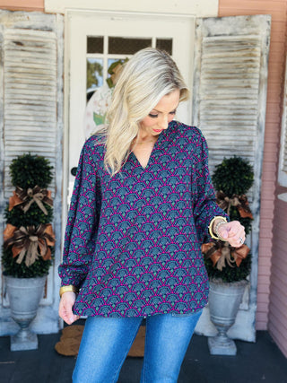 "Aria Second Glance Pink Top with geometric floral print in pink, teal, and navy"

"Women’s patterned blouse with V-neckline and long sleeves"

"Aria Second Glance Pink Top featuring bold pink and teal print with relaxed silhouette"