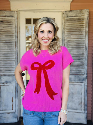 Bright pink knit Lilah Top with red bow detail on front, short sleeves

Women’s pink sweater top with textured red bow design, casual chic style

Close-up of pink knit Lilah Top fabric with raised red bow applique

Short sleeve pink knit top with bold red bow graphic, women’s fashion

Lilah Top pink sweater styled with jeans for everyday wear
