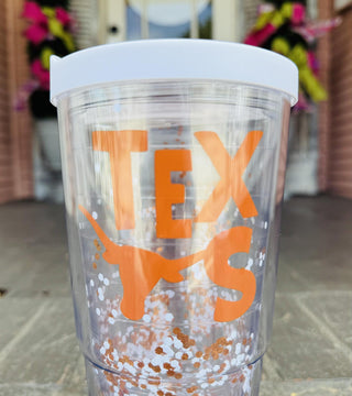 Clear Texas tumbler with burnt orange logo, white lid, and floating glitter