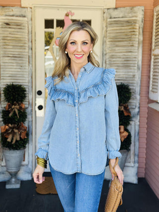 Woman wearing light denim ruffle button-up top

Chambray ruffle yoke denim blouse with collar

Josie Denim Top with shirred ruffle detail

Light blue high-low hem denim shirt for women

Feminine chambray button-up with long sleeves