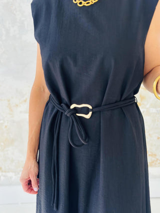 Woman wearing Miley Black Dress, sleeveless black midi dress with gold belt accent

Miley Black Dress with muscle shoulder design and slit hem

Black midi dress with gold embellished belt and back keyhole closure

Elegant sleeveless black dress styled with strappy heels