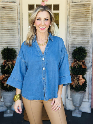 Relaxed denim button-down top with v-neck and wide sleeves

Millie Denim Top in soft blue with quarter sleeves

Casual chambray-style denim blouse with snap buttons

Oversized denim shirt with wide sleeves and v-neckline

Blue denim button top with flowy quarter-length sleeves