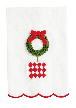 White cotton slub hand towel featuring a French knot embroidered wreath topiary with a red velvet bow, red diamond planter, and embroidered scalloped red hem.