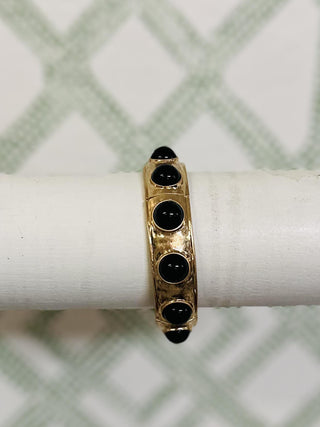 Gold bangle bracelet with glossy black bead accents on white display

Close-up of gold and black bead stretch bracelet on bracelet stand

Hammered gold bangle with round black beads in circular design

