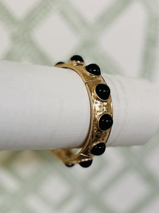 Gold bangle bracelet with glossy black bead accents on white display

Close-up of gold and black bead stretch bracelet on bracelet stand

Hammered gold bangle with round black beads in circular design


