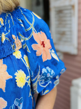 Blue floral mini dress with split V-neckline, ruffle sleeves, and tiered hem.