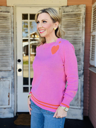 Pink knit sweater with orange heart detail on chest

Maryam Heart Sweater in pink with striped hem and heart graphic

Women’s bright pink sweater with orange heart and stripe accents

Pink heart sweater with ribbed cuffs and contrast hem
