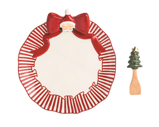 Santa Bow Cookie Plate Set featuring a hand-painted ceramic cookie plate with a dimensional red bow and Santa accent, plus a wooden spatula with a ceramic Christmas tree handle.
