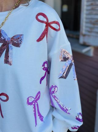 White Lilian Bow Sweater with pink and red sequin bows

Holiday sweater with sparkly sequin bows in pink and red

White festive sweater with multicolor bow embellishments

Lilian Bow Sweater featuring sequin ribbon details

White Christmas bow sweater with shimmering sequin design