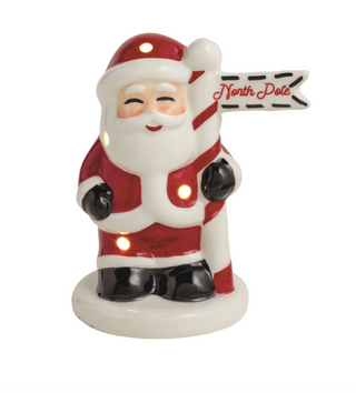 Hand-painted ceramic Santa Light-Up Sitter with built-in LED lights, classic red suit, and North Pole sign on a white display base.