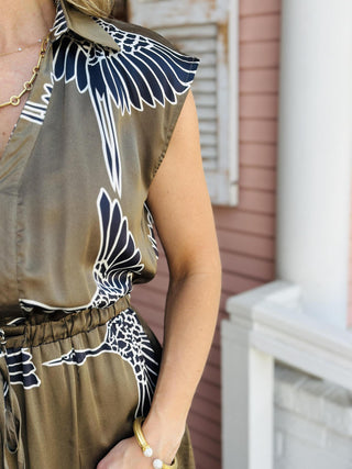 Indie Dress in olive with white bird print and tiered maxi silhouette

Cap sleeve maxi dress with collar, V-neckline, and self-tie waist

Olive green tiered maxi dress featuring bold white bird pattern

Indie Dress with collared V-neck, tiered skirt, and waist tie

Sleeveless maxi dress with cap sleeves and statement bird print