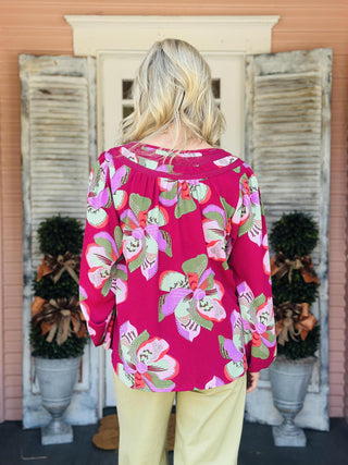 "Janelle Center Stage Plum Top with bold floral print and long sleeves"

"Plum blouse with oversized pink and green floral pattern and ruffle neckline"

"Women’s floral long sleeve top in plum with gathered neckline and relaxed fit"
