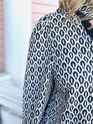 “Woman wearing the Kayla Blouse with black and ivory geometric print and contrast collar.”

“Long-sleeve patterned Kayla Blouse styled with black pants outside boutique.”

“Kayla Blouse with modern black-and-cream print and v-neck collar detail.”

“Geometric print blouse with puff sleeves and contrast neckline on model.”

“Chic black and ivory Kayla Blouse for work or everyday wear.”