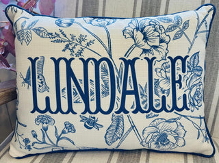 Lindale decorative throw pillow with bold navy lettering, blue botanical illustrations, and navy piping.