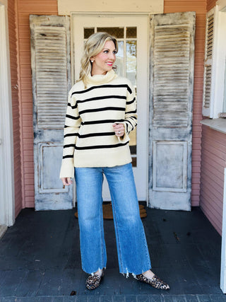 Cream and black striped turtleneck Nylah Sweater on model

Women’s striped turtleneck sweater with long sleeves and split cuffs

Neutral stripe cozy knit turtleneck sweater for fall and winter

Cream sweater with black stripes and relaxed fit turtleneck