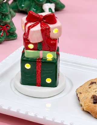 Hand-painted ceramic Present Light-Up Sitter featuring stacked Christmas gift boxes with red, green, and pink wrapping, glitter ribbon accents, and built-in LED lights.