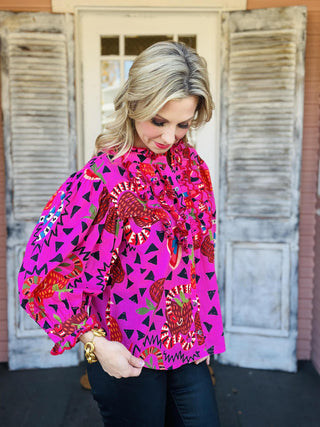Bright pink Sabrina Charming Top with ruffles and bold print

Colorful patterned blouse with snakes, hearts, and ruffled neckline

Pink ruffle-front top with vibrant artistic print

Statement blouse with whimsical multicolor pattern and buttons