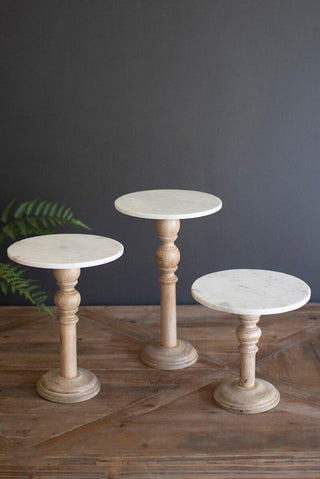 “Wooden display stands with white marble tops in three heights”