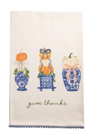 Cream cotton hand towel with embroidered blue chinoiserie pumpkin topiaries, "Give Thanks" sentiment, and blue mini pom-pom trim.