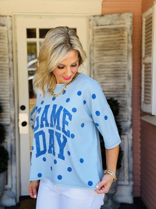 Light blue oversized Game Day graphic short sleeve top with navy polka dots, side slits, and bold varsity-inspired "GAME DAY" lettering.