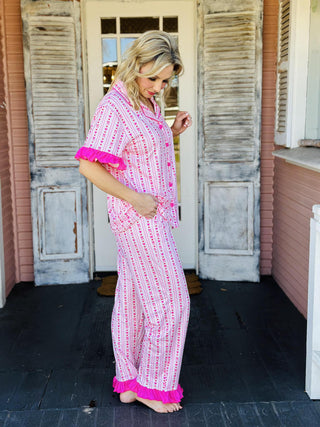 Oh So Lovely Pajama Pants Set with pink heart print, ruffled sleeves, and ruffle hem pants

Pink button-down pajama set with heart pattern and ruffle details

Women’s ruffled pajama pants set with drawstring waist and button-front top

Romantic heart print pajama set with ruffled sleeves and pant cuffs