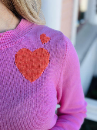 Pink knit sweater with orange heart detail on chest

Maryam Heart Sweater in pink with striped hem and heart graphic

Women’s bright pink sweater with orange heart and stripe accents

Pink heart sweater with ribbed cuffs and contrast hem
