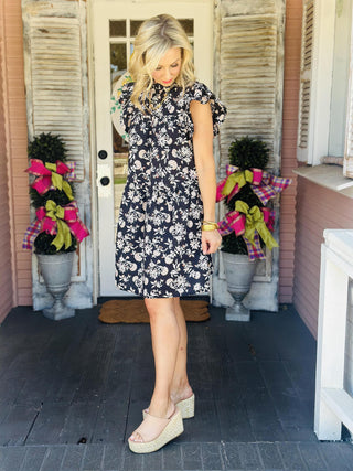 Woman wearing floral ruffle neck dress with flutter sleeves

Gabriela cotton cambric dress with short flutter sleeves and fall floral print