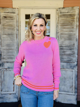Pink knit sweater with orange heart detail on chest

Maryam Heart Sweater in pink with striped hem and heart graphic

Women’s bright pink sweater with orange heart and stripe accents

Pink heart sweater with ribbed cuffs and contrast hem