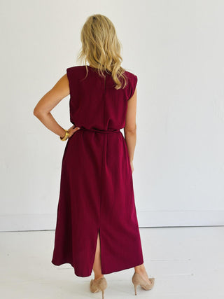 Woman wearing Miley Burgundy Dress, sleeveless burgundy midi dress with gold belt accent

Miley Burgundy Dress with muscle shoulder design and slit hem

Burgundy midi dress with gold embellished belt and back keyhole closure

Elegant sleeveless burgundy dress styled with strappy heels