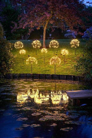 Solar powered garden stake lights shaped like dandelions glowing at night