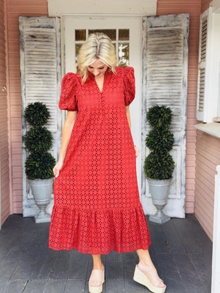 Katrina Dress in rust eyelet fabric featuring short puff sleeves, a ruffled mock neckline, button-front closure, and midi-length ruffle hem.