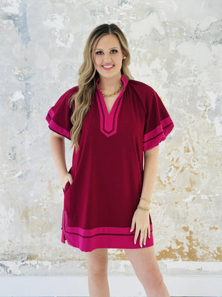 Woman wearing Amanda Dress in burgundy with pink contrast accents

Short lantern sleeve Amanda mini dress with split collar band

Amanda Dress in woven mid-weight fabric with slit hem

Stylish burgundy pullover mini dress with contrast detailing